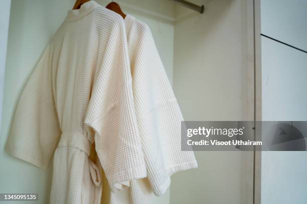 fresh white bathrobes hanging on rack. - bath robe stockfoto's en -beelden