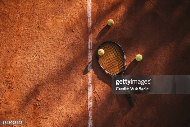 racchetta da tennis e palline da tennis su campo in terra battuta - terreno di gioco foto e immagini stock