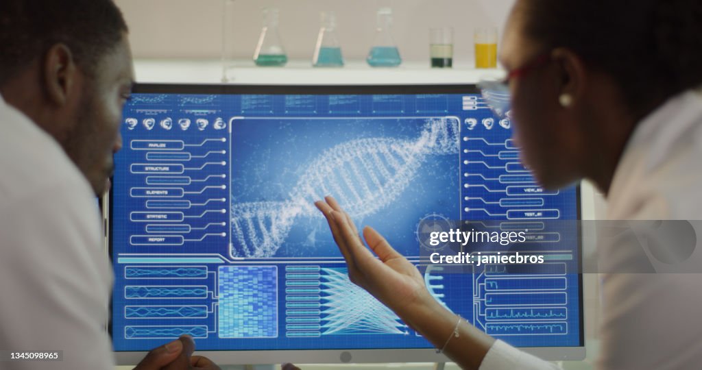 African ethnicity scientists studying DNA samples. Computer screens with DNA sequences. Discussing