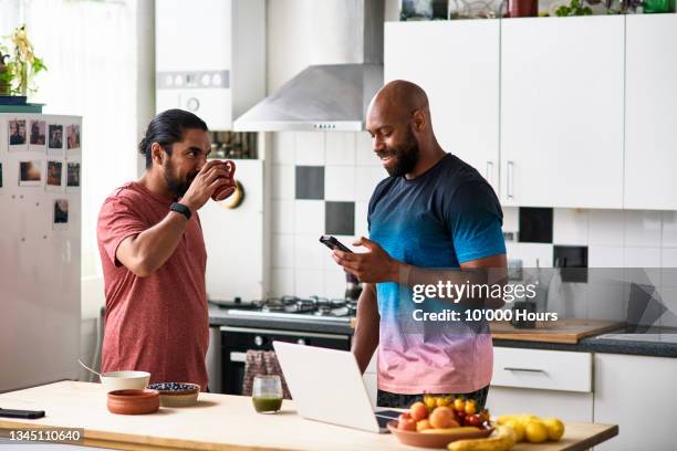male flatmates having breakfast, one using phone - männer über 30 stock-fotos und bilder