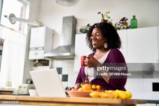 cheerful mid adult woman using laptop and smiling in online meeting - breakfast with the best stock-fotos und bilder