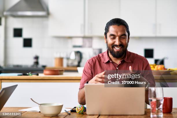 mid adult man using laptop in kitchen - skype call stock pictures, royalty-free photos & images