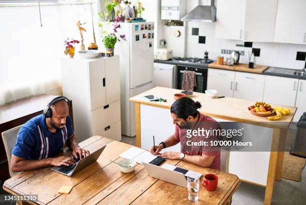 high angle of two flat mates working from home - adaptation stock pictures, royalty-free photos & images