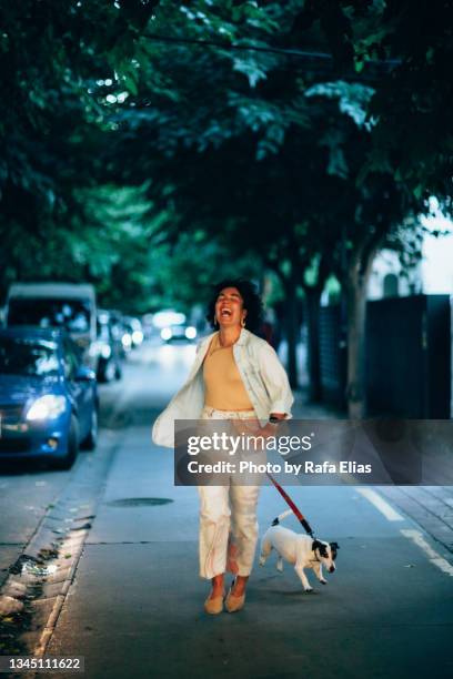 happy woman running with her dog along the street - jack russel photos et images de collection