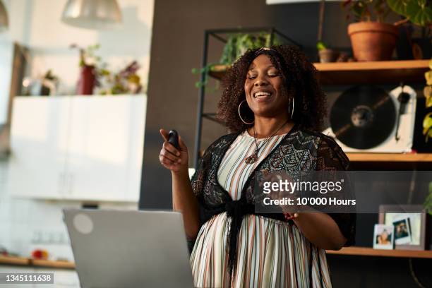 mid adult woman giving online presentation from home - woman portrait kitchen laptop stock-fotos und bilder