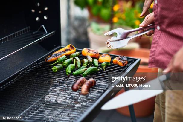close up of man barbecuing chilli peppers on grill - grilled stock pictures, royalty-free photos & images