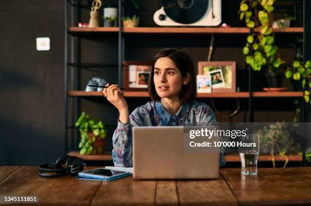 mid adult businesswoman using laptop and looking away - contemplation home stock-fotos und bilder