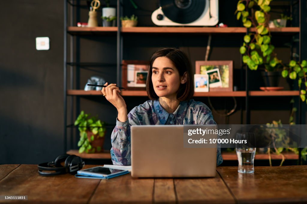 Mid adult businesswoman using laptop and looking away