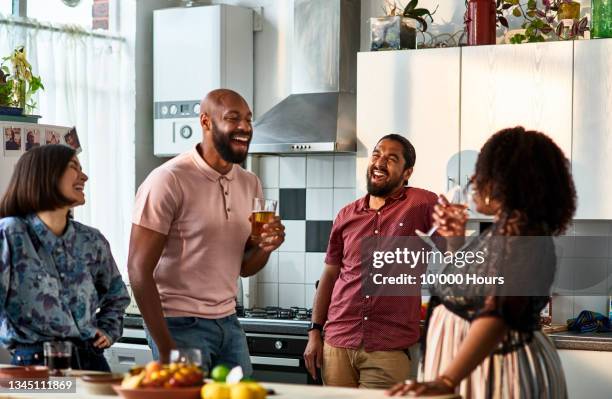 multi ethnic friends socialising in domestic kitchen - avond thuis stockfoto's en -beelden