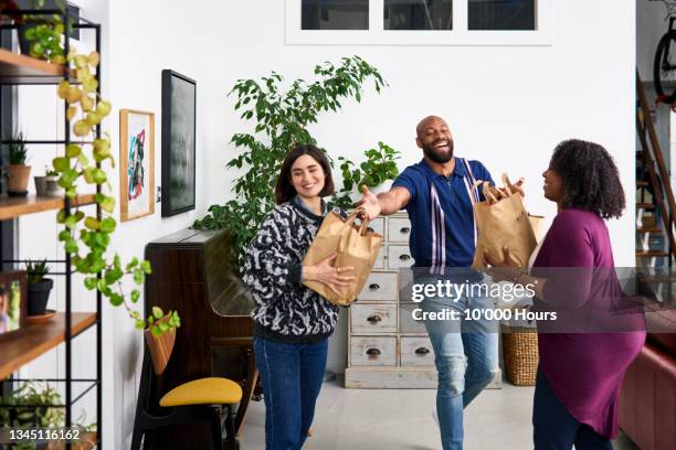 man handing takeaway paper bags to female friends - delivery character stock pictures, royalty-free photos & images