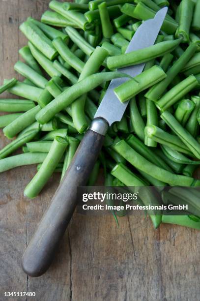 string beans with a knife on a wooden chopping board - ベニバナインゲン ストックフォトと画像