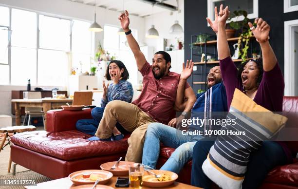 four friends watching sport on tv and cheering - stream stock pictures, royalty-free photos & images