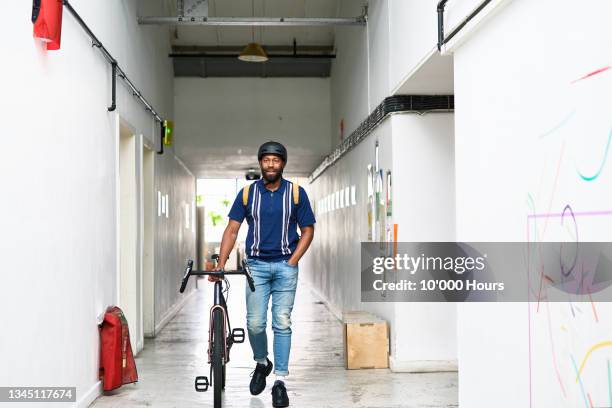 mid adult man pushing bike through corridor - pushing bike stock pictures, royalty-free photos & images