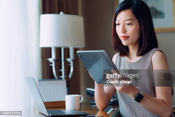 young asian businesswoman using digital tablet while sitting at her desk in office. remote working, freelancer, small business ideas. female leadership. making business connections with technology - business phone meeting bildbanksfoton och bilder