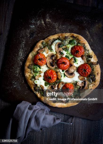 a vegetarian pizza with tomatoes, mushrooms, pesto and mozzarella - vegetarian pizza stock pictures, royalty-free photos & images