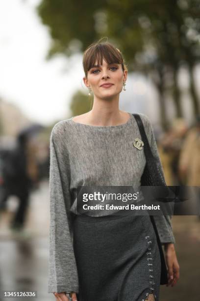 Model wears Chanel earrings, a pale gray wool large sleeves pullover with a Chanel pearls brooch, high waist dark gray nailed / studded split / slit...