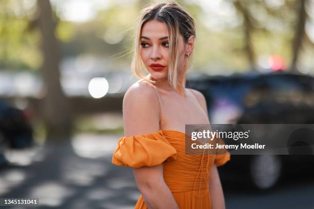 Madelyn Cline wearing orange dress outside Giambattista Valli Show on October 04, 2021 in Paris, France.