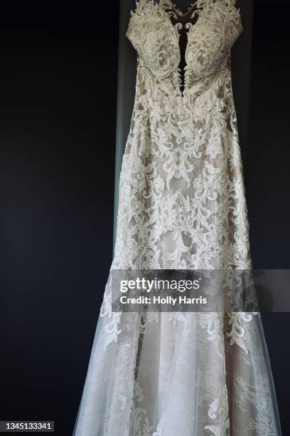 lace wedding dress hanging against a gray wall - frilly stock pictures, royalty-free photos & images