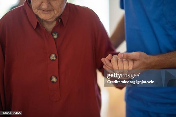 enfermera atenta que ayuda a una mujer mayor a caminar en un hogar de ancianos - old woman young man fotografías e imágenes de stock