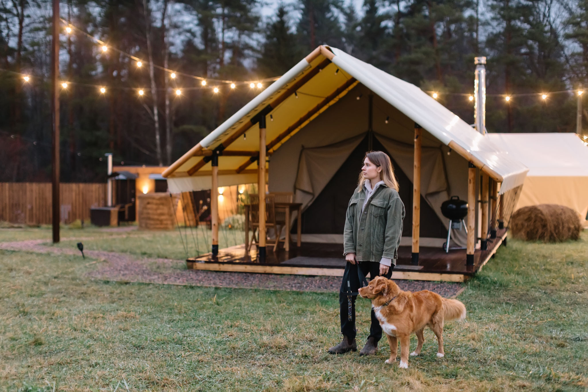 Handsome girl in green jacket walking with brown Nova Scotia Duck Tolling Retriever on green meadow. Handsome girl in green jacket walking with brown Nova Scotia Duck Tolling Retriever on green meadow.