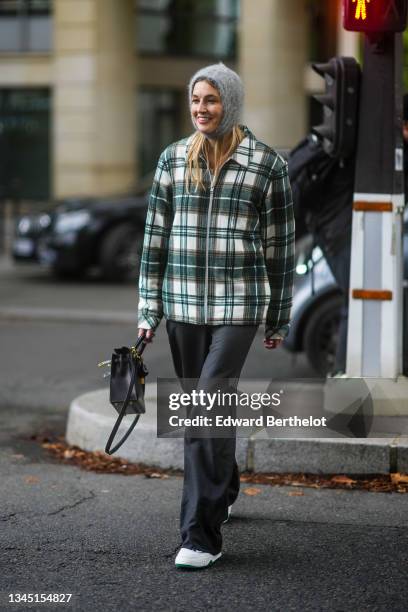 Camille Charriere wears a pale gray hood / balaclava wool, a white / dark green / brown checkered print pattern wool oversized shirt, dark gray large...