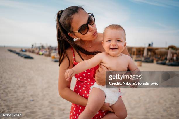 mom walks with her son by the beach - baby suncream stockfoto's en -beelden