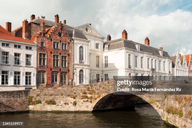 old stone bridge and houses of famous flemish medieval city brugge in autumn time. - belgium canal stockfoto's en -beelden