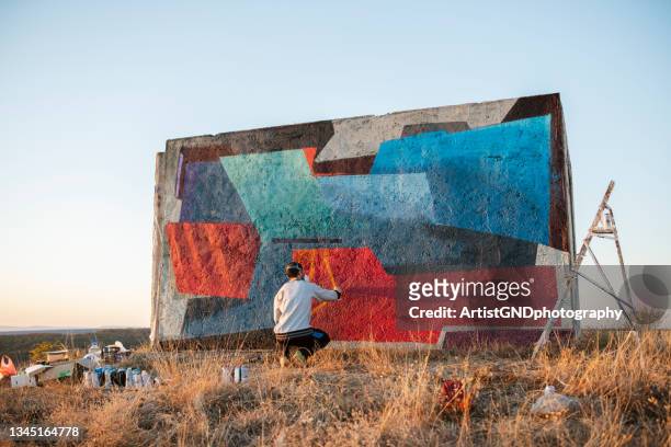 graffiti street artist is painting on wall in nature. - streetart imagens e fotografias de stock