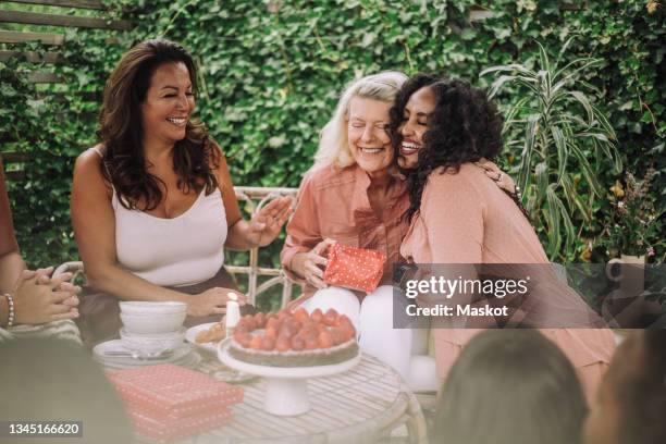 smiling daughter embracing mother in birthday party - daughter birthday stock pictures, royalty-free photos & images