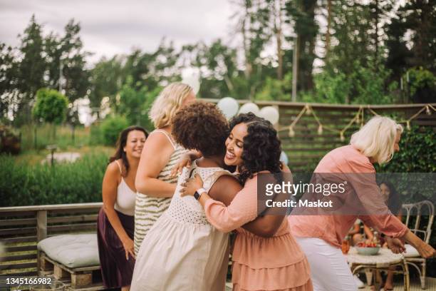 smiling mother embracing daughter in birthday party - older woman birthday stock pictures, royalty-free photos & images