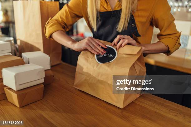 woman packing food for delivery - food safety packaging stock pictures, royalty-free photos & images