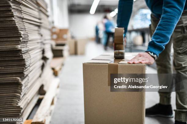 operaio maschio che nastra la scatola di cartone - cardboard box foto e immagini stock