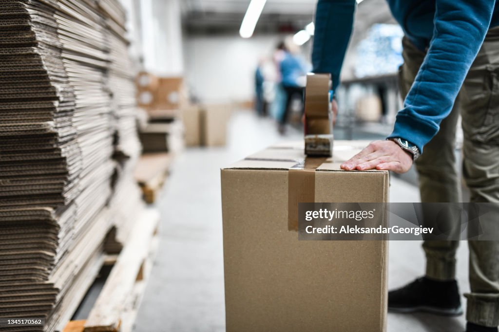 Male Worker Taping Cardboard Box