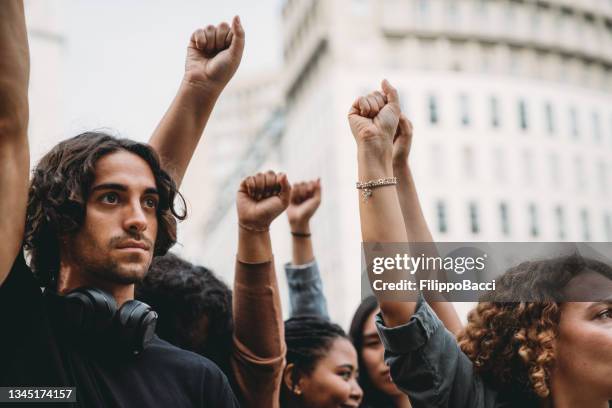 people with raised fists at a demonstration in the city - political rally stock pictures, royalty-free photos & images