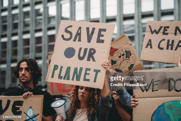 a group of young adult people are marching together on strike against climate change - climate change conference stock pictures, royalty-free photos & images