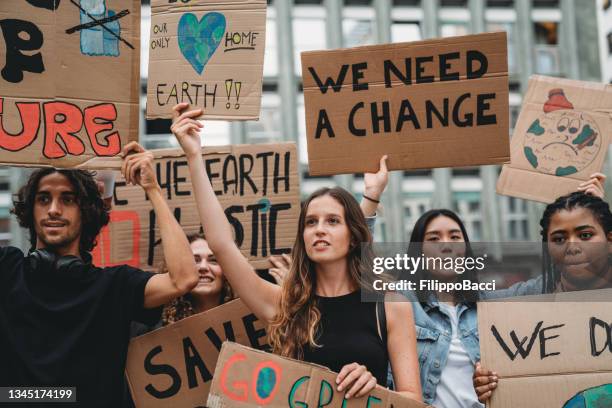 un gruppo di giovani adulti sta marciando insieme in sciopero contro il cambiamento climatico - protest foto e immagini stock