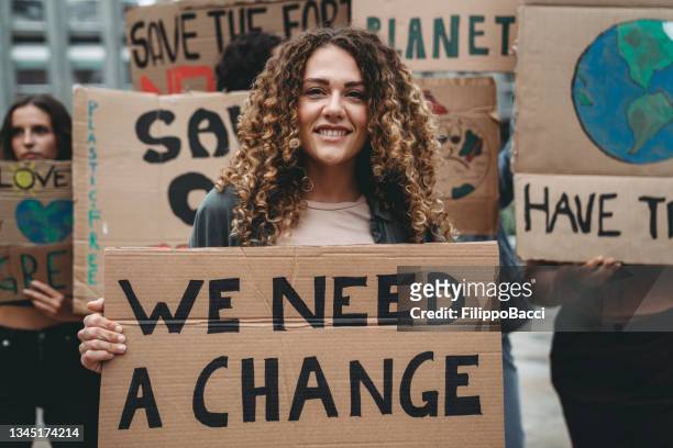 a group of young adult people are marching together on strike against climate change - demonstration stockfoto's en -beelden