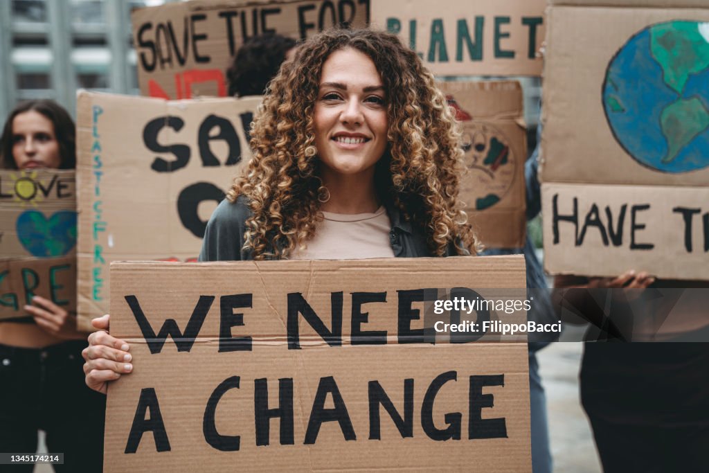 A group of young adult people are marching together on strike against climate change