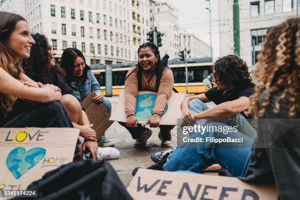 a group of young adult people are resting after a climate change demonstration in the city - protestor stock pictures, royalty-free photos & images