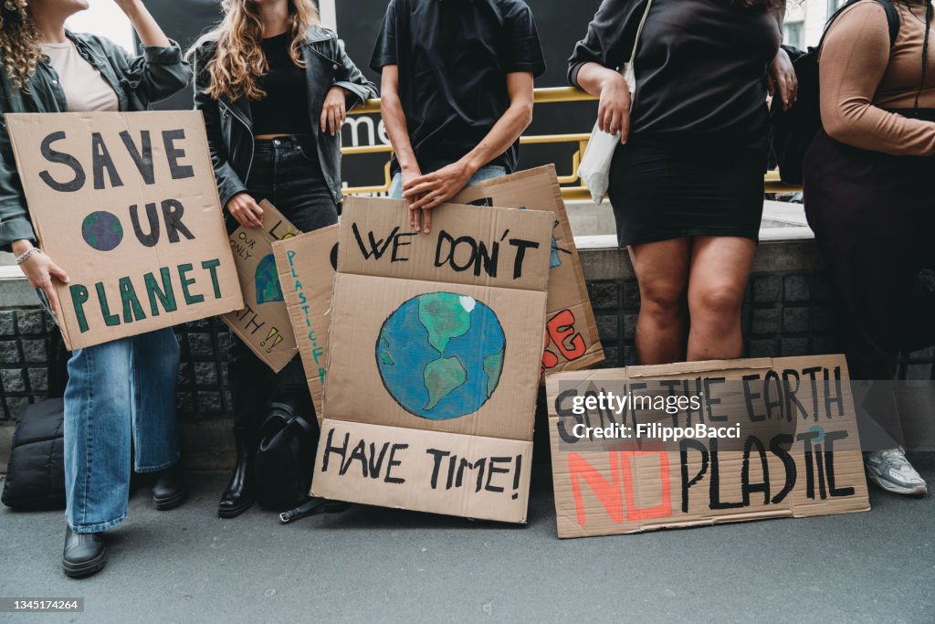 Menschen halten Bannerschilder hoch, während sie zu einer Demonstration gegen den Klimawandel gehen