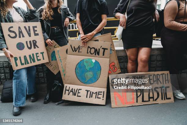 people are holding banner signs while they are going to a demonstration against climate change - demonstration stockfoto's en -beelden