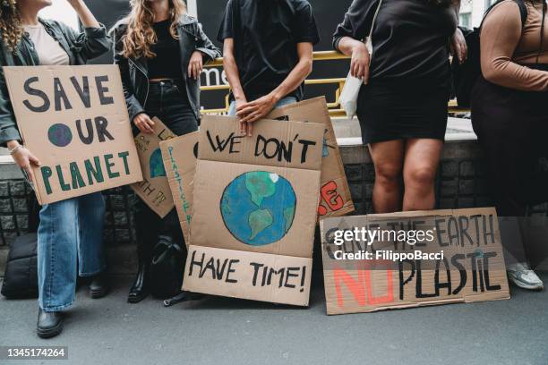 people are holding banner signs while they are going to a demonstration against climate change - protestor stock pictures, royalty-free photos & images