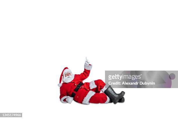 santa claus lies and points his hand to the free space on a white background isolate. sale concept for christmas and new year advertisements - santa claus lying stockfoto's en -beelden