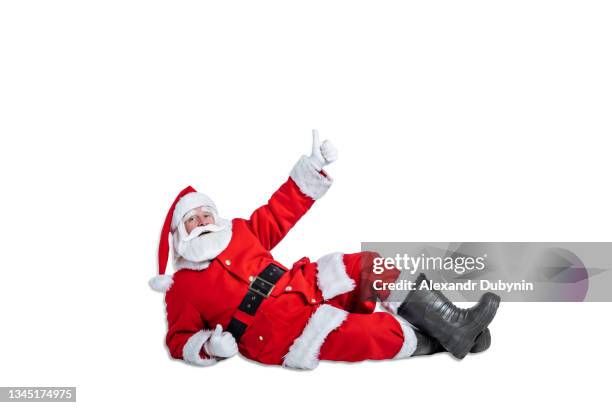 santa claus lies on the floor and shows thumbs up hand gesture on white background isolate. christmas advertising and sale concept - papá noel fotografías e imágenes de stock