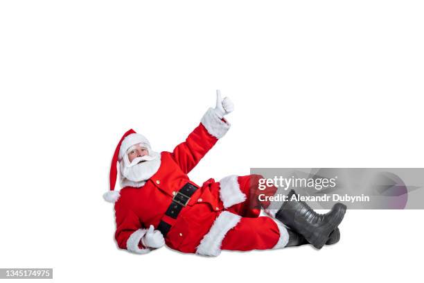 santa claus lies on the floor and shows thumbs up hand gesture on white background isolate. christmas advertising and sale concept - santa claus lying stock pictures, royalty-free photos & images