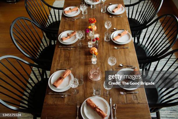 plates with wineglasses arranged on dinner table in dining room - thanksgiving table stockfoto's en -beelden