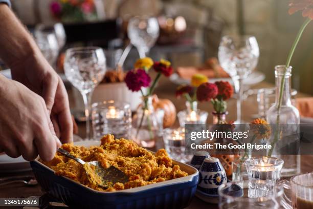 young man serving fresh prepared food on dining table during thanksgiving - thanksgiving plate stock pictures, royalty-free photos & images