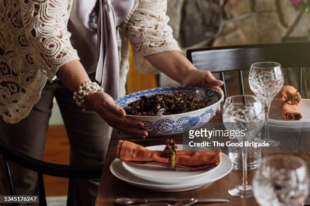 mature woman bring food to table on thanksgiving - thanksgiving day stock-fotos und bilder