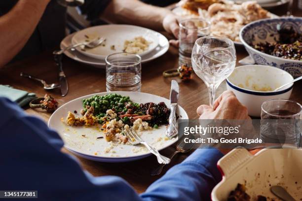 senior man sitting with food and wineglass at dining table - vreten stockfoto's en -beelden