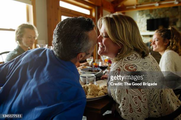 Affectionate couple embracing each other while sitting in dining room at home